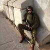 Soldier resting against a stone wall, gear on