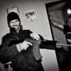 Member snapshot posing with a gun in-frame