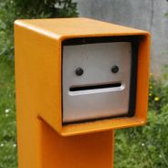 A quirky orange mailbox with a face-like design