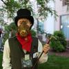 Steampunk-costumed man clutching a lit pipe outdoors
