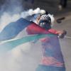 Protester amid smoke, gas mask and flag draped
