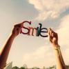 Holding up hands spelling out SMILE against sky