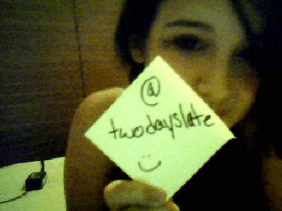 Member holds handwritten Twitter handle note, smiling