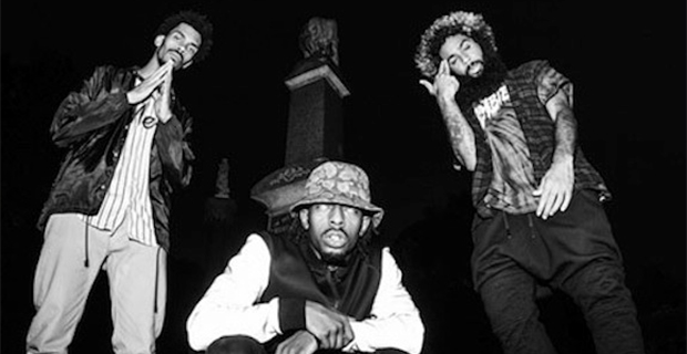Three guys posing by a monument at night