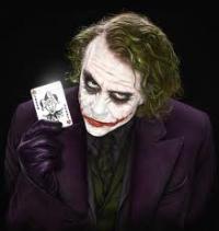 The Joker holds up his card, grinning menacingly