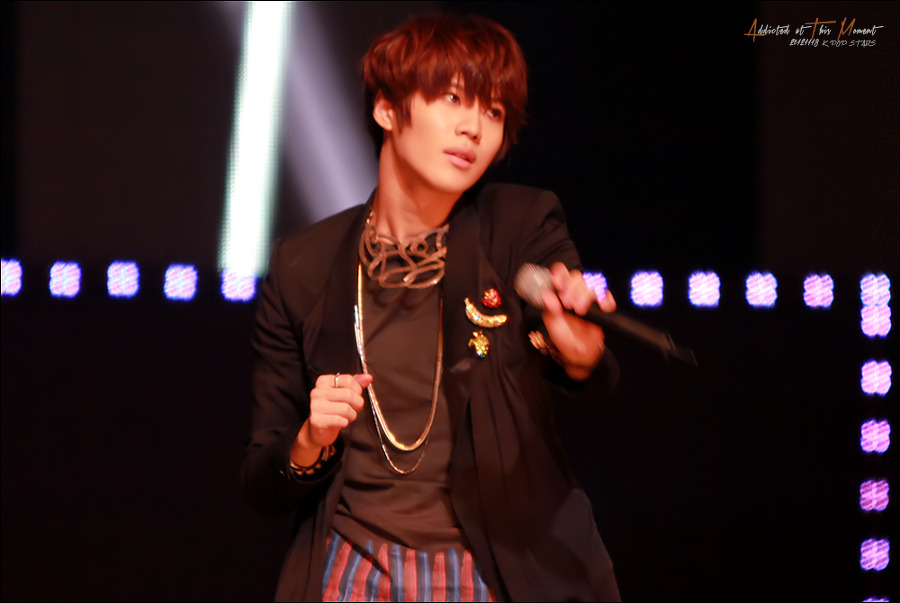 K-pop performer mid-concert, mic in hand on stage